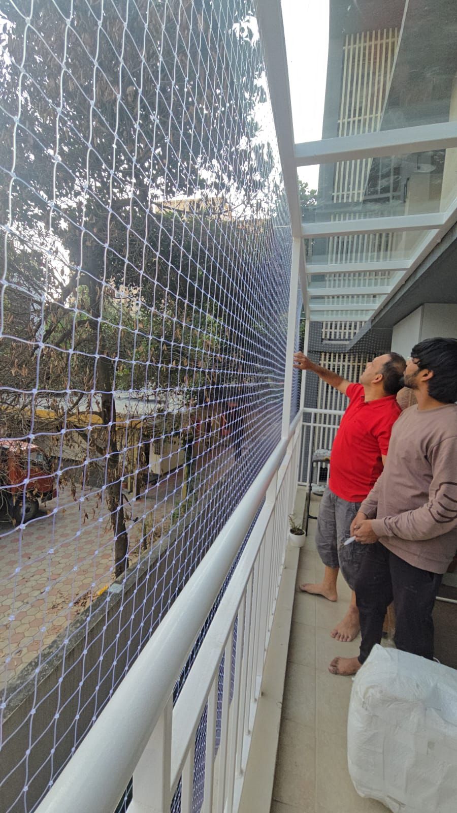 Technicians installing balcony safety net at a residential apartment
